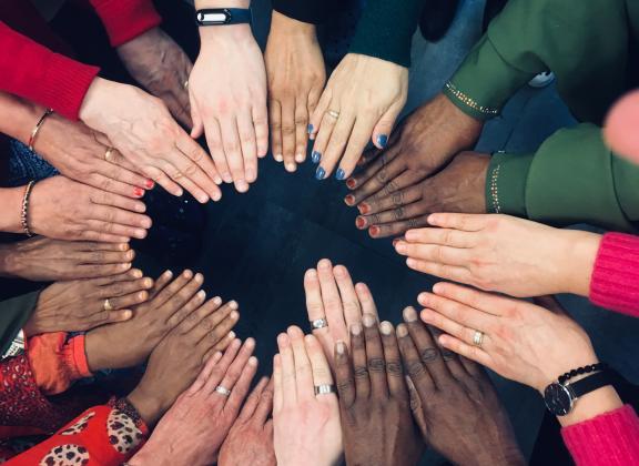 Ihmisten käsiä ympyränmuotoisessa muodostelmassa.